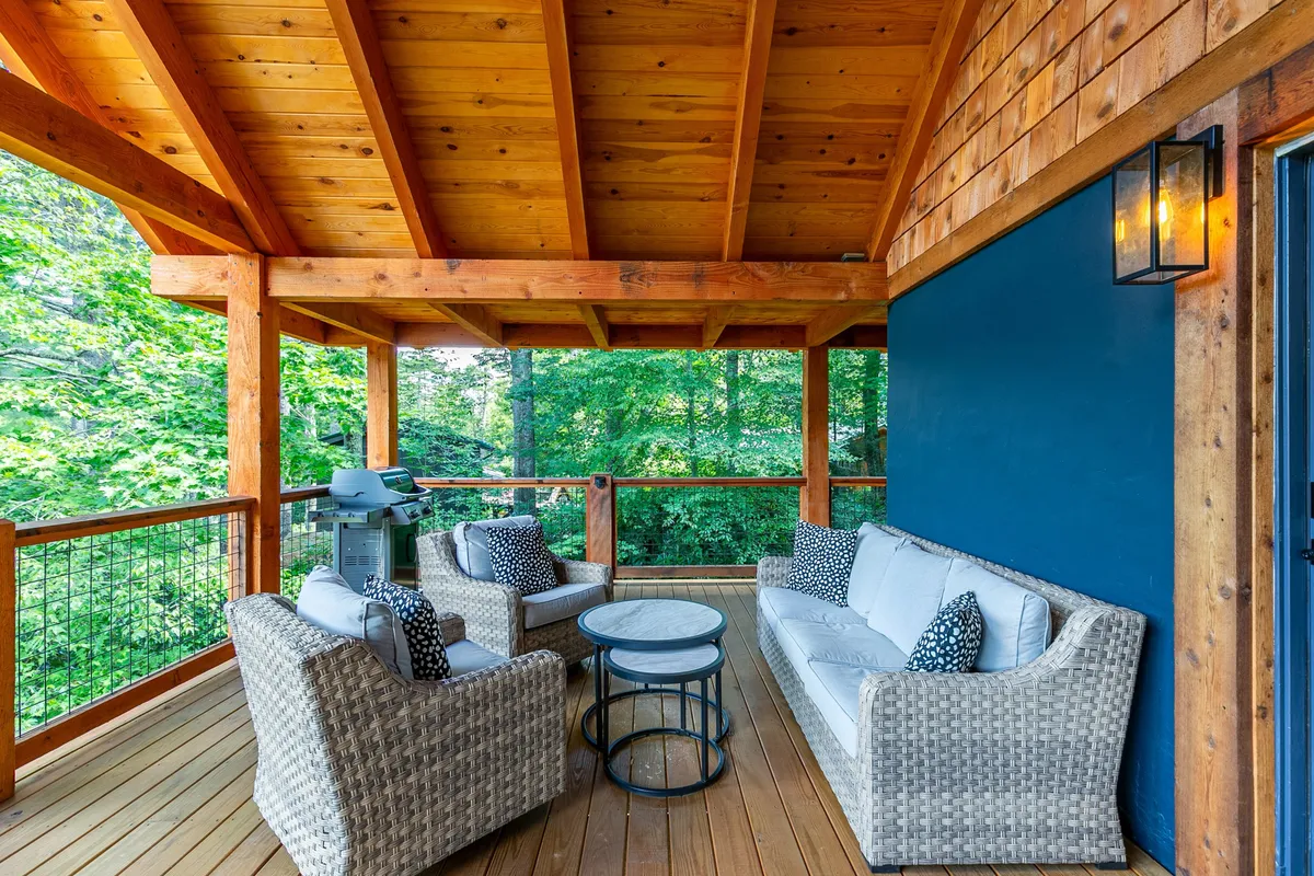 An inviting outdoor seating area with comfortable chairs, a wooden ceiling overhead, and lush greenery in the background. The setting is tranquil and appears perfect for relaxing after a day of adventure, offering a seamless connection to the surrounding nature.