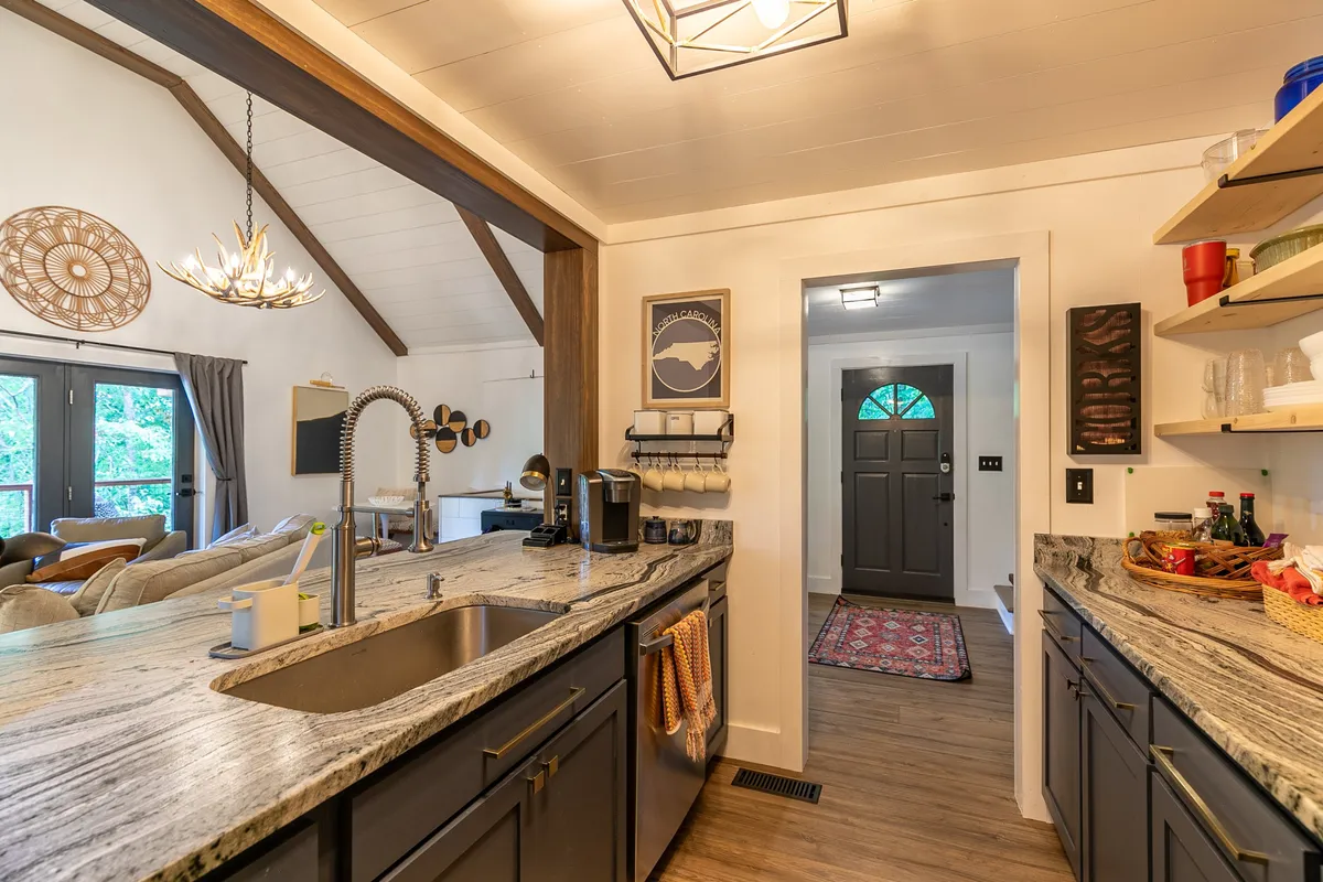 The image presents a modern, fully renovated kitchen with a granite countertop, kitchen sink, and open layout. Decorative wall art and an inviting atmosphere suggest a space perfect for preparing and sharing group meals, a central theme in the section's narrative.